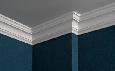 Close up of ceiling corner, finished with crown molding and wallpaper