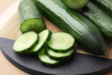 Fresh whole and cut cucumbers on beige background, closeup