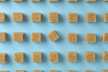Brown sugar cubes on light blue background, flat lay