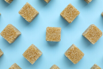 Brown sugar cubes on light blue background, flat lay