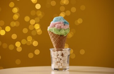 Sweet cotton candy in waffle cone on table against blurred lights