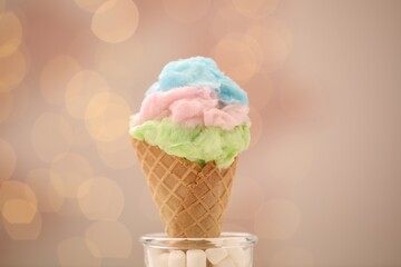 Sweet cotton candy in waffle cone against blurred lights, closeup