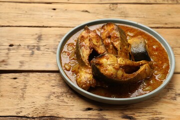 Tasty fish curry on wooden table, closeup. Space for text. Indian cuisine