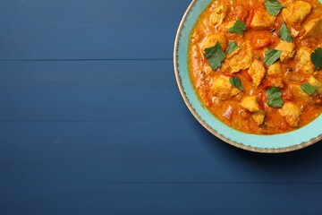 Delicious chicken curry on blue wooden table, top view. Space for text