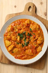 Delicious chicken curry on wooden table, top view