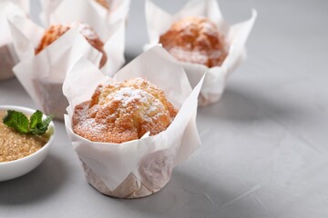 Delicious muffins with powdered sugar on grey table, closeup