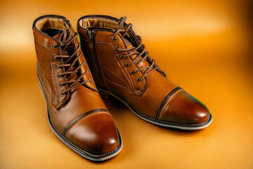 A pair of premium calfskin boots on a yellow background. Horizontal shot.