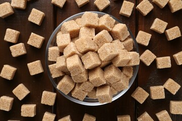 Brown sugar cubes on wooden table, flat lay