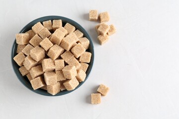 Brown sugar cubes on white table, flat lay. Space for text