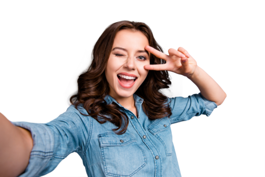 Self-portrait of nice cute cheerful lovely attractive magnificent brunette girl with wavy hair in casual denim shirt, opened mouth, showing v-sign near eye, isolated over grey background