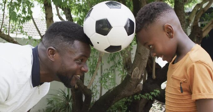African American father and son enjoy a playful moment outdoors with a soccer ball