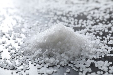 Heap of natural salt on black table, closeup