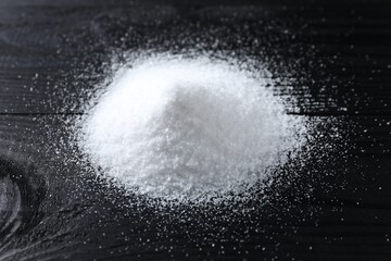 Pile of organic salt on black wooden table, closeup
