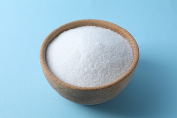 Organic white salt in bowl on light blue background