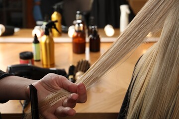 Hairdresser combing client's hair in salon, closeup