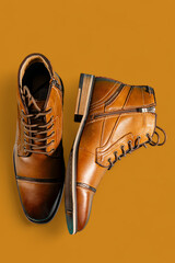 A pair of premium calfskin boots on a brown background. Vertical shot.