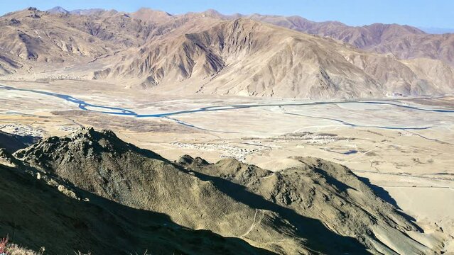 GANDEN MONASTERY, TIBET: general view, colorful buildings on sunny hill side and tibetan prayer flags, sunny dry winter landscape