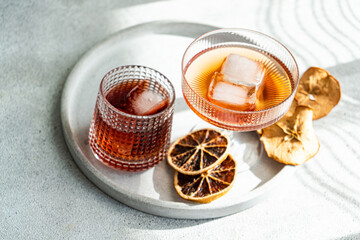A well-lit, elegant presentation of various alcoholic drinks in ribbed glasses, accented with ice cubes and dried citrus on a circular tray