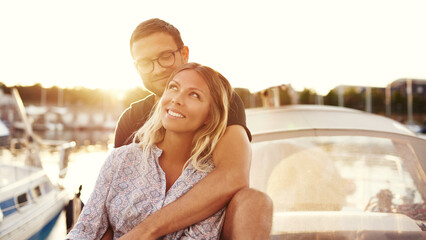 Happy smiling couple sitting together on a boat in the sunset - 740676288