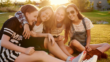 A group of laughing teenage girls hanging out together on a summer evening outdoors