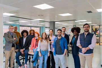 A diverse group of professionals smiling and posing together in a contemporary coworking office...
