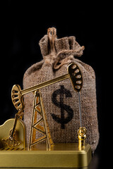 Gold miniature oil pump and money bag with US dollar symbol