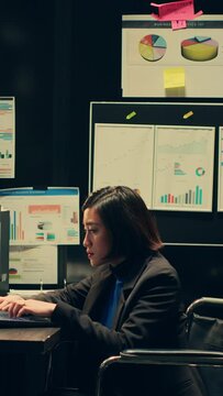 Vertical Video Wheelchair user and inspector analyzing criminal records in police archive room, cross reference data from cases to identify similarities. Team of agents compile notes on crime trends