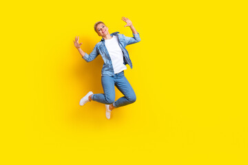 Fototapeta na wymiar Full length photo of lovely young lady jumping raise hands excited dressed stylish denim garment isolated on yellow color background