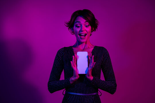 Photo portrait of pretty young girl hold down white screen dressed stylish overall outfit isolated on neon light pink color background