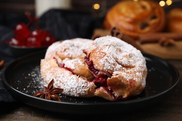 Delicious buns with berries, sugar powder and anise star on table, closeup
