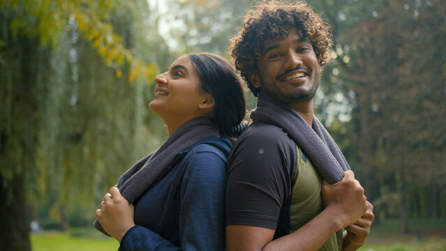 Indian friends Arabian couple man woman girl guy female male sport people standing together in park sunny outdoors in city wipe sweat with towel smiling relax after sporty workout running exercise