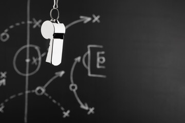 Referee whistle against chalkboard with game scheme, closeup. Space for text