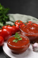 Organic ketchup in bowls and fresh tomatoes on table, closeup. Tomato sauce