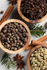 Different aromatic spices and fir branches on light textured table, flat lay