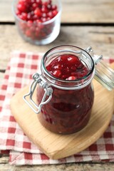 Fresh cranberry sauce in glass jar on light wooden table