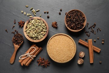 Different spices in bowls on dark gray textured table, flat lay