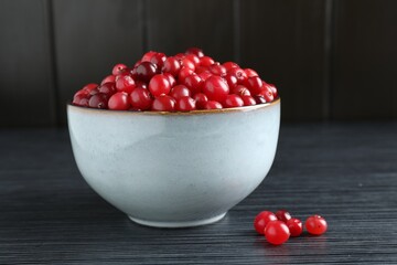 Cranberries in bowl on black wooden table, closeup