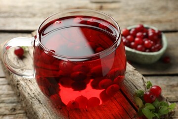 Delicious cranberry tea and berries on wooden table, closeup