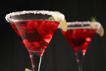 Tasty cranberry cocktail in glasses against black background, closeup