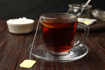 Brewing tea. Glass cup with tea bag on wooden table, closeup