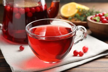 Tasty hot cranberry tea in glass cup and fresh berries on wooden table