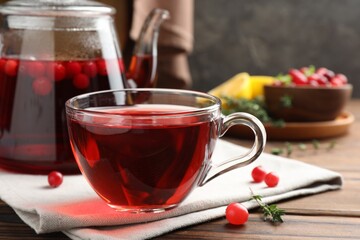 Tasty hot cranberry tea in glass cup and fresh berries on wooden table