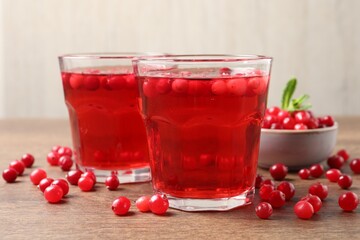 Tasty cranberry juice in glasses and fresh berries on wooden table, closeup