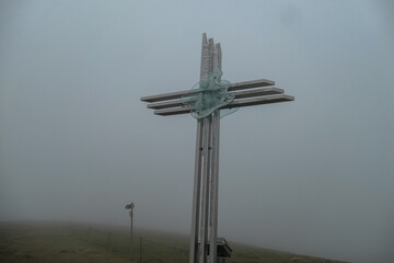 Summit cross of mountain peak Hornischegg in Mur Valley, Lavanttal Alps, Styria, Austria. Serene atmosphere in remote Austrian Alps. Cloudy day. Dark clouds accumulating to a storm. No visibility