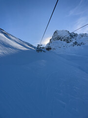Chairlift with sun peeking out behind the hills in Lech am Arlberg in wintertime