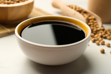 Soy sauce in bowl on white table, closeup