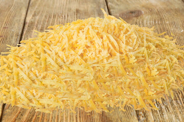 cheddar cheese,  piece of cheese isolated. grated Cheddar Cheese as close up view top and side view for industrial cheese products. Selective focus Cheese on wooden board on table