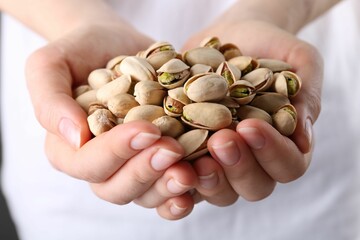 Woman holding handful of tasty pistachios, closeup