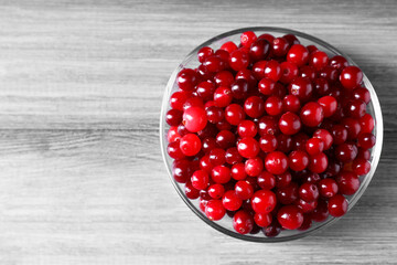 Fresh ripe cranberries in bowl on grey wooden table, top view. Space for text