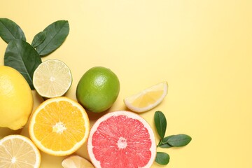 Different cut and whole citrus fruits on yellow table, flat lay. Space for text